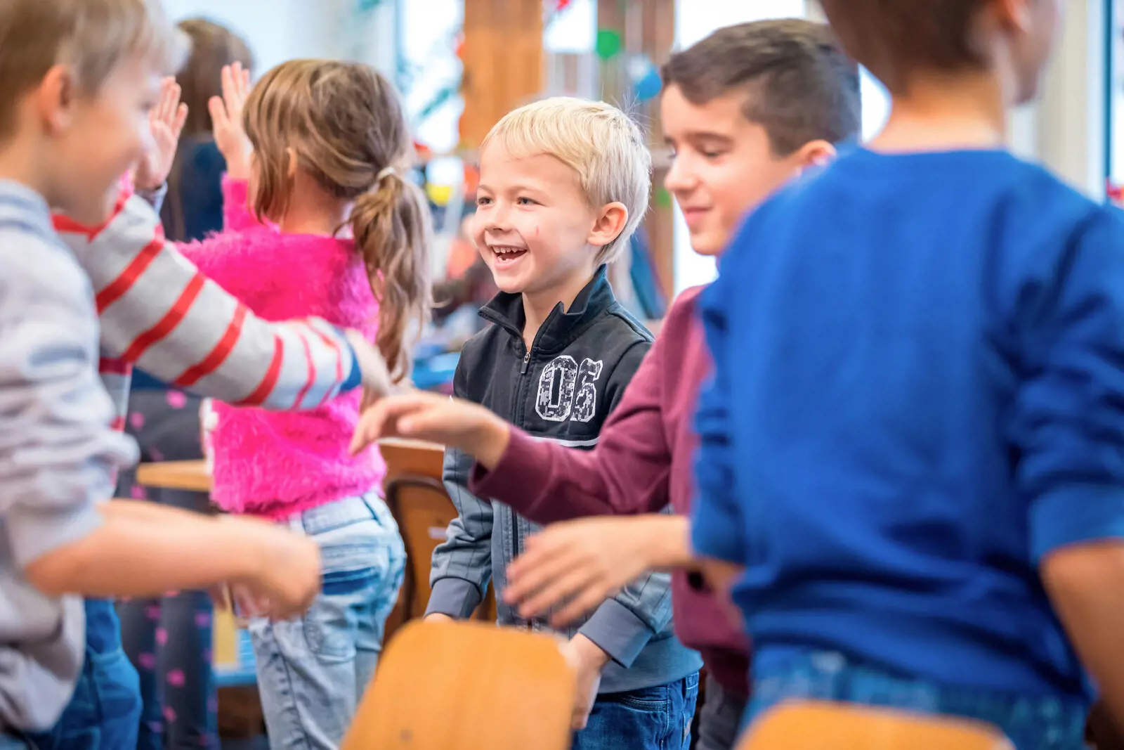 Children play with each other. A blonde in the center of the picture smiles.