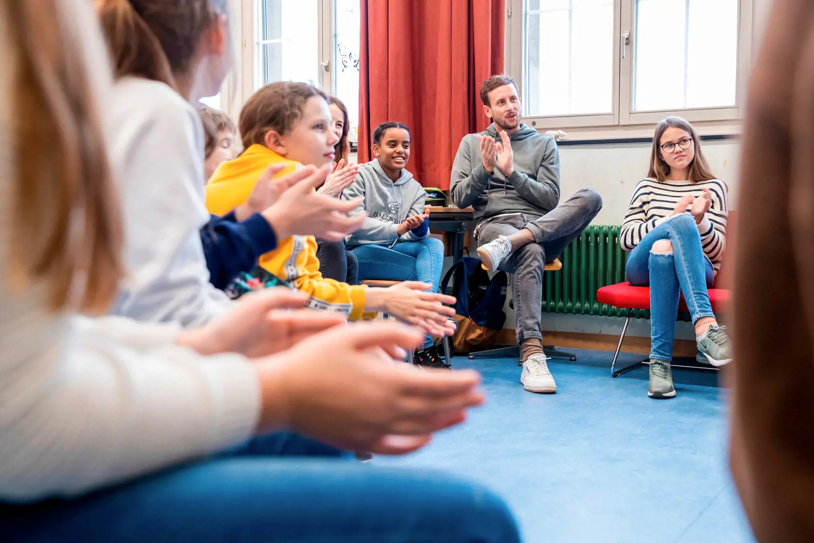 A teacher and his students sit in a circle.