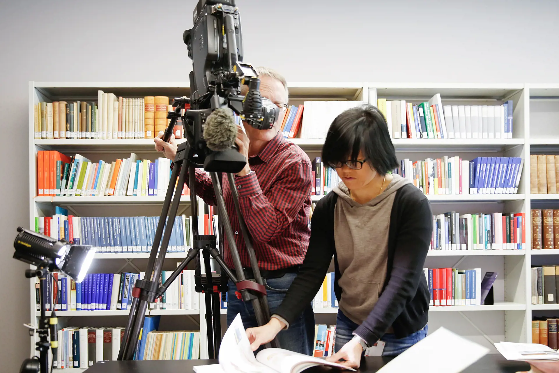 Two people are engaged in archiving books.