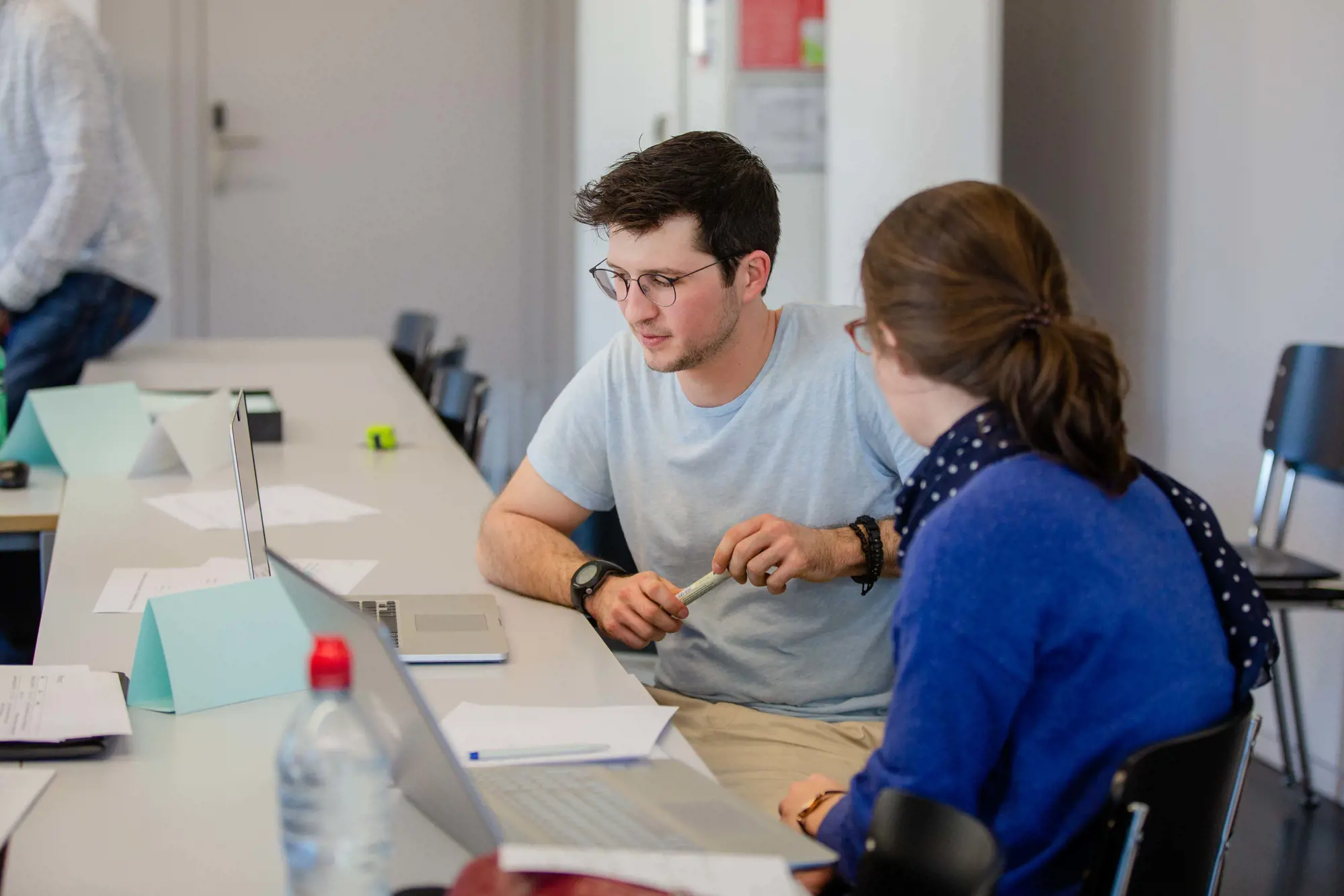 Two people are talking in front of a laptop.