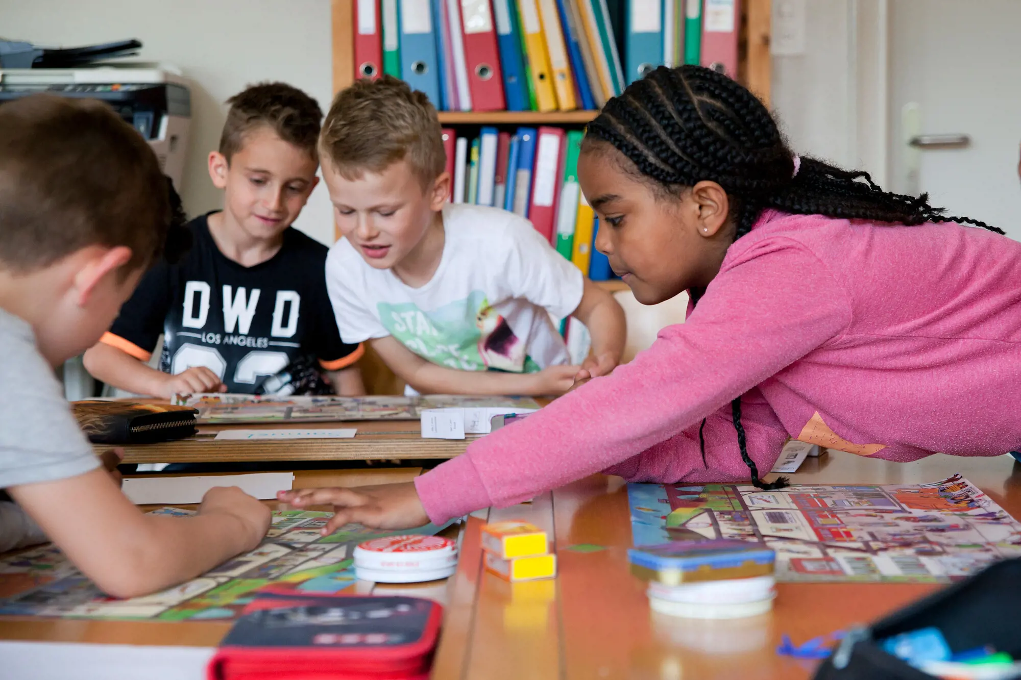 A group of children sitting on the ground. They are all using tablets and being instructed by a teacher.