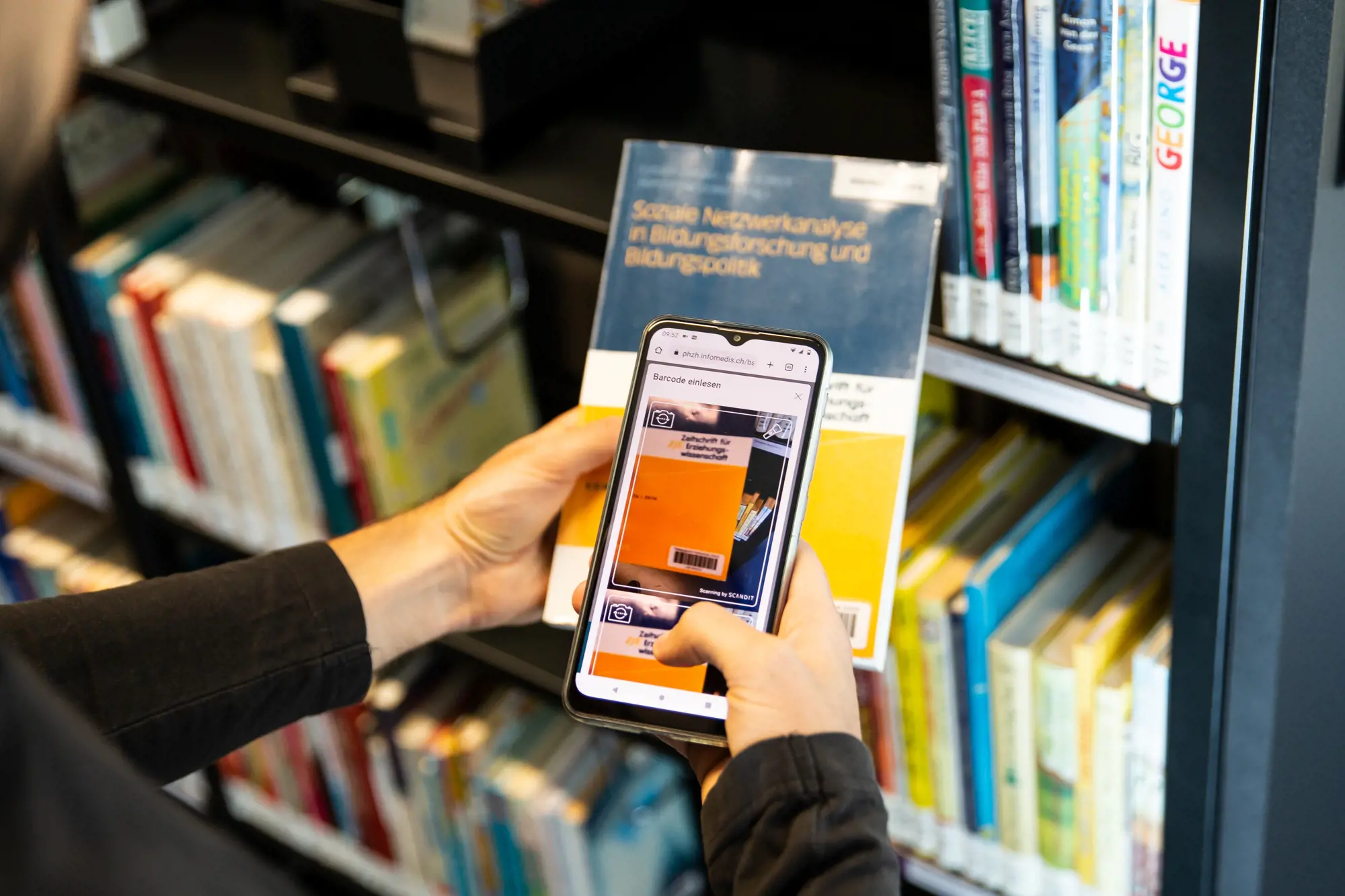 Bibliotheksbesucher scannt Buchsignatur mit Handy ein, um es auszuleihen