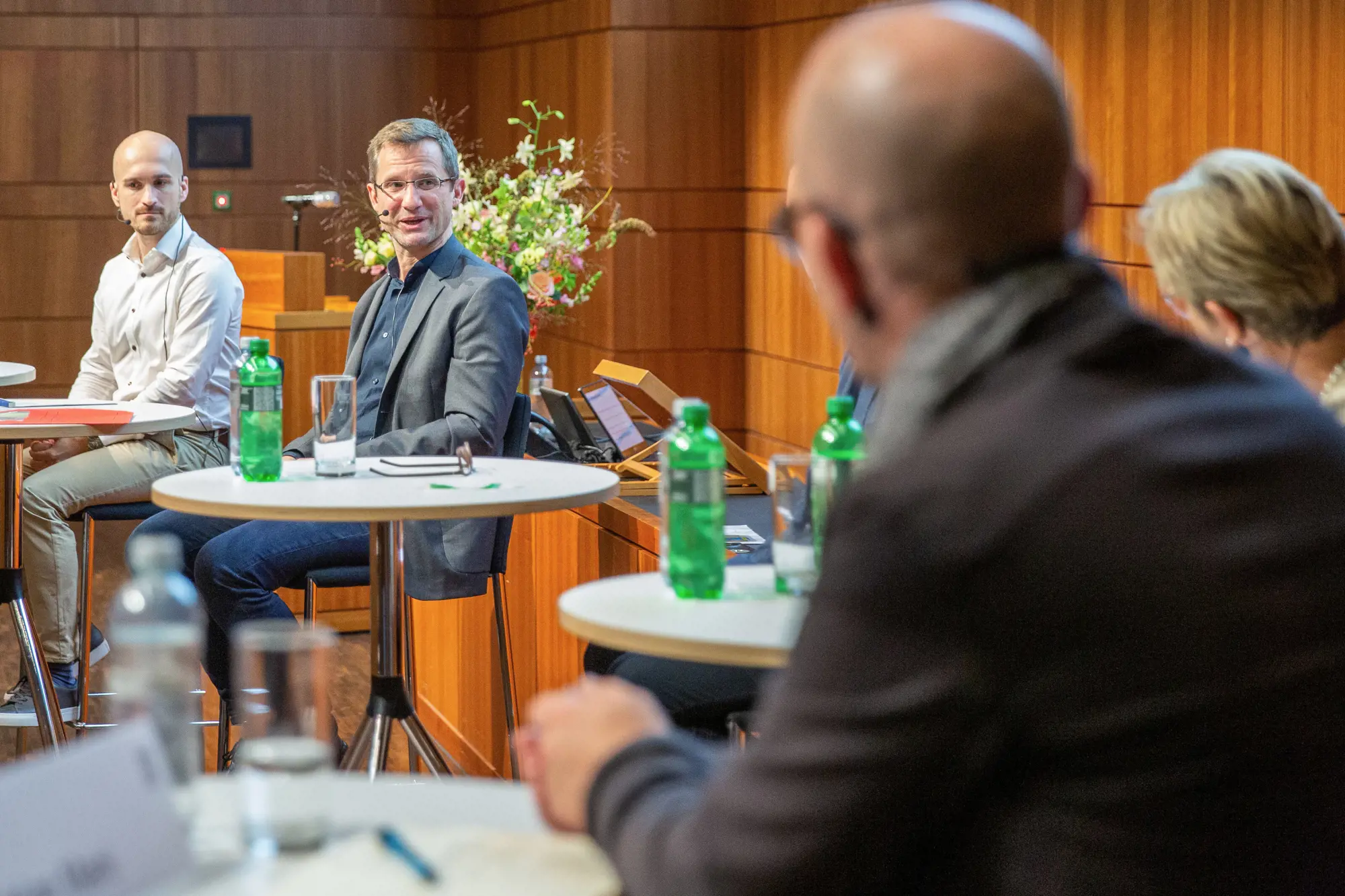 Podiumsteilnehmer unterhalten sich. Im Fokus steht ein Mann.