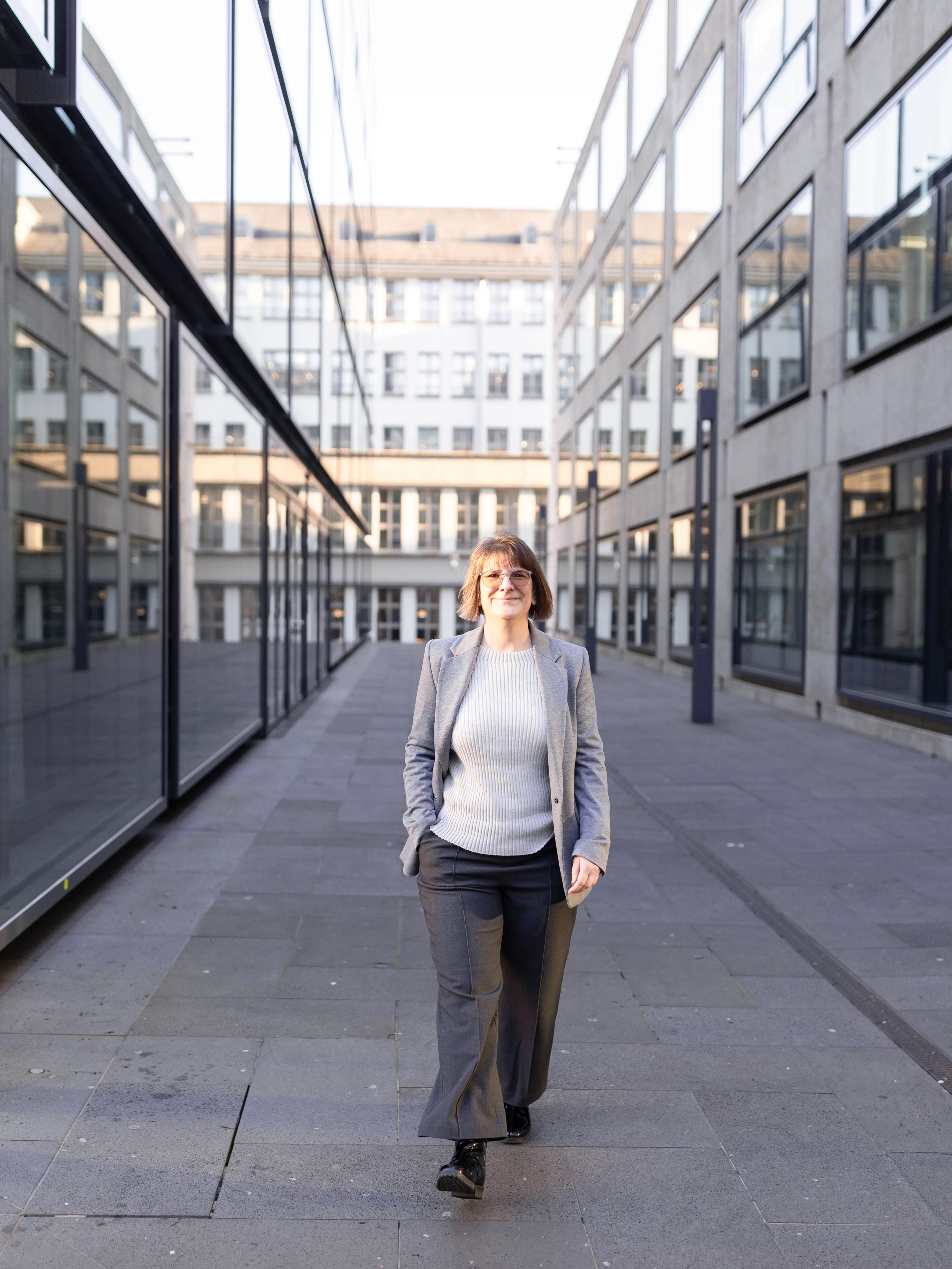 Andrea Schweizer spaziert auf dem Campusplatz der PH Zürich zwischen zwei Gebäuden.
