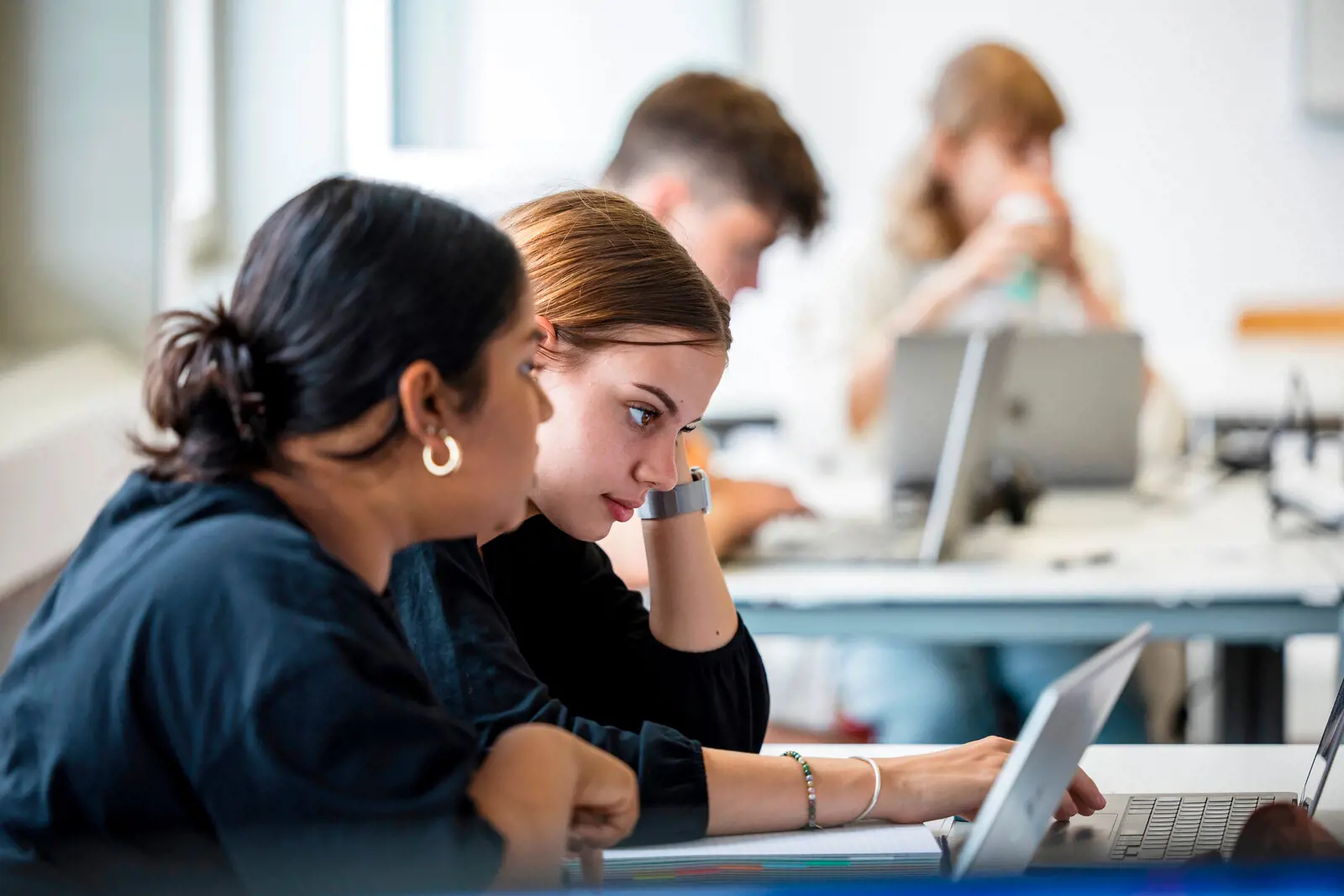 Two students look at the laptop.