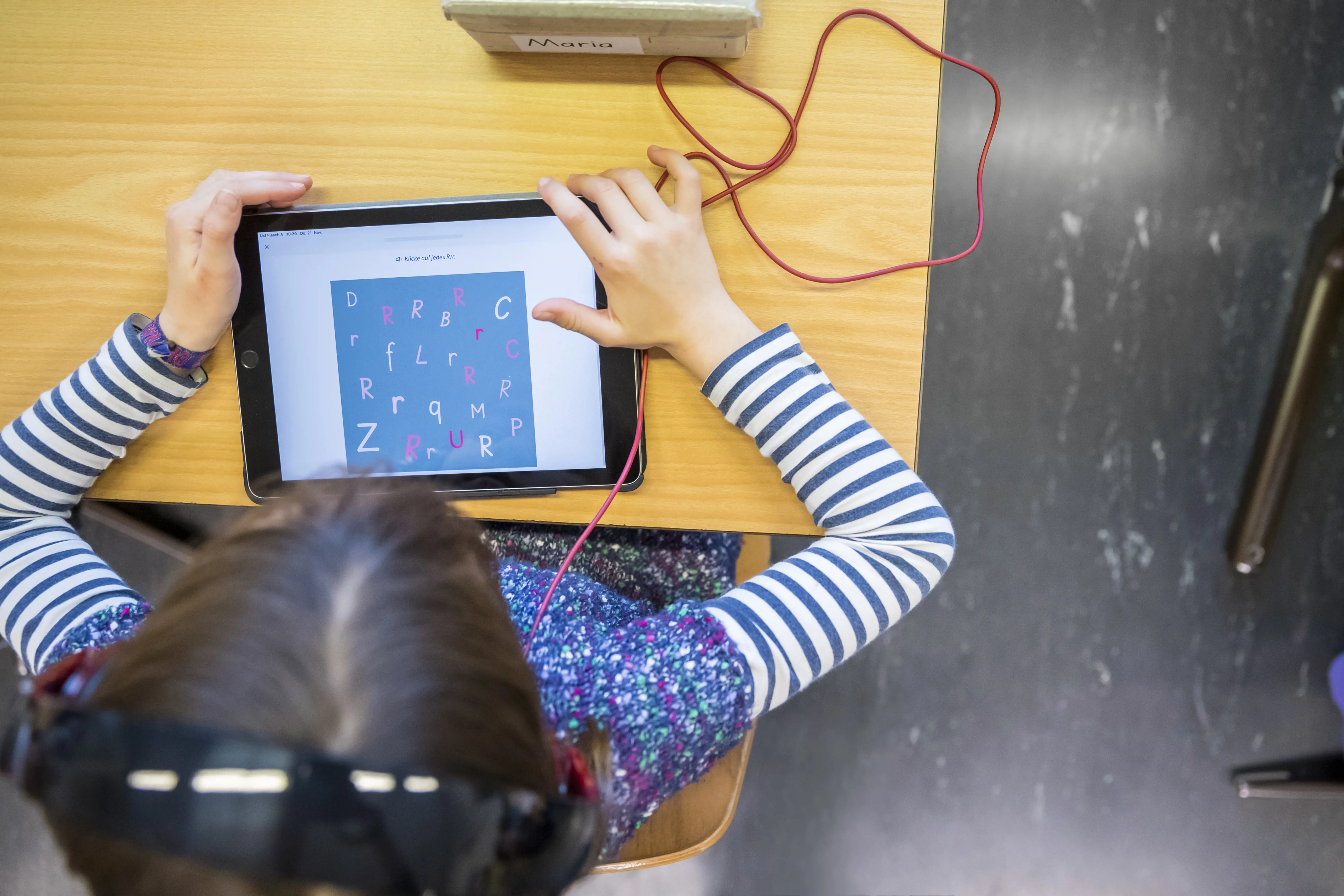 Aus der Vogelperspektive sieht man ein Schulkind an einem Tablet arbeiten.