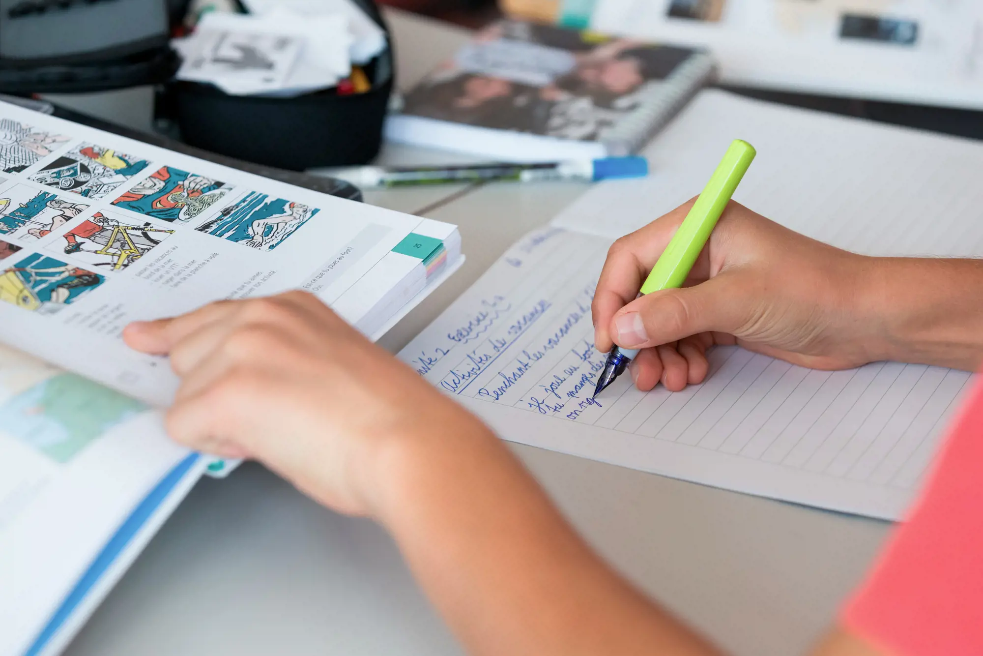 A young student writes something in French in a book.