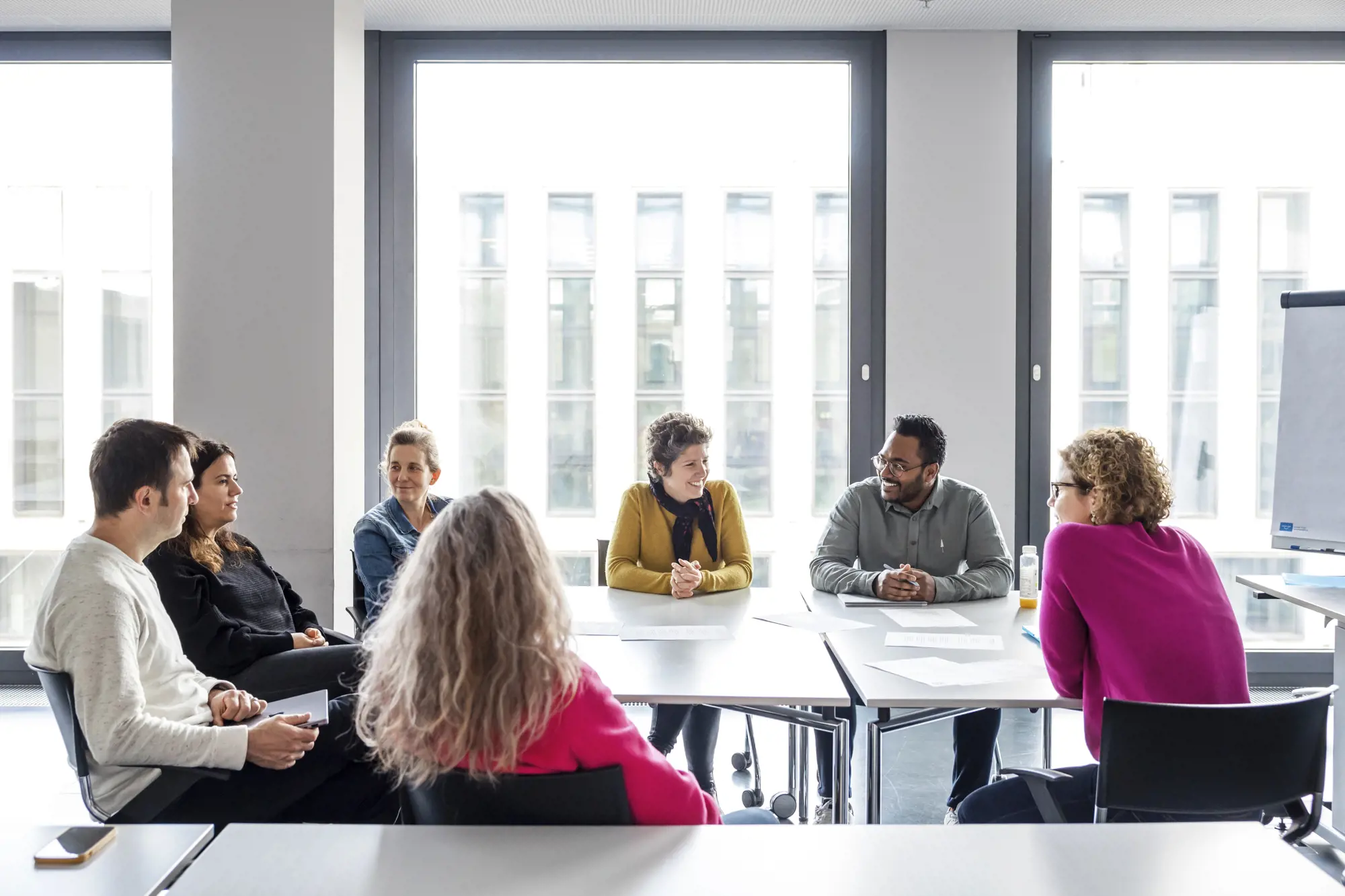 A group of people are sitting in a meeting room discussing a topic.