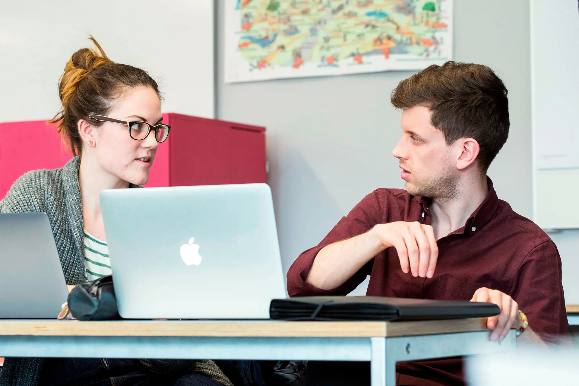 Two people are talking at a desk.