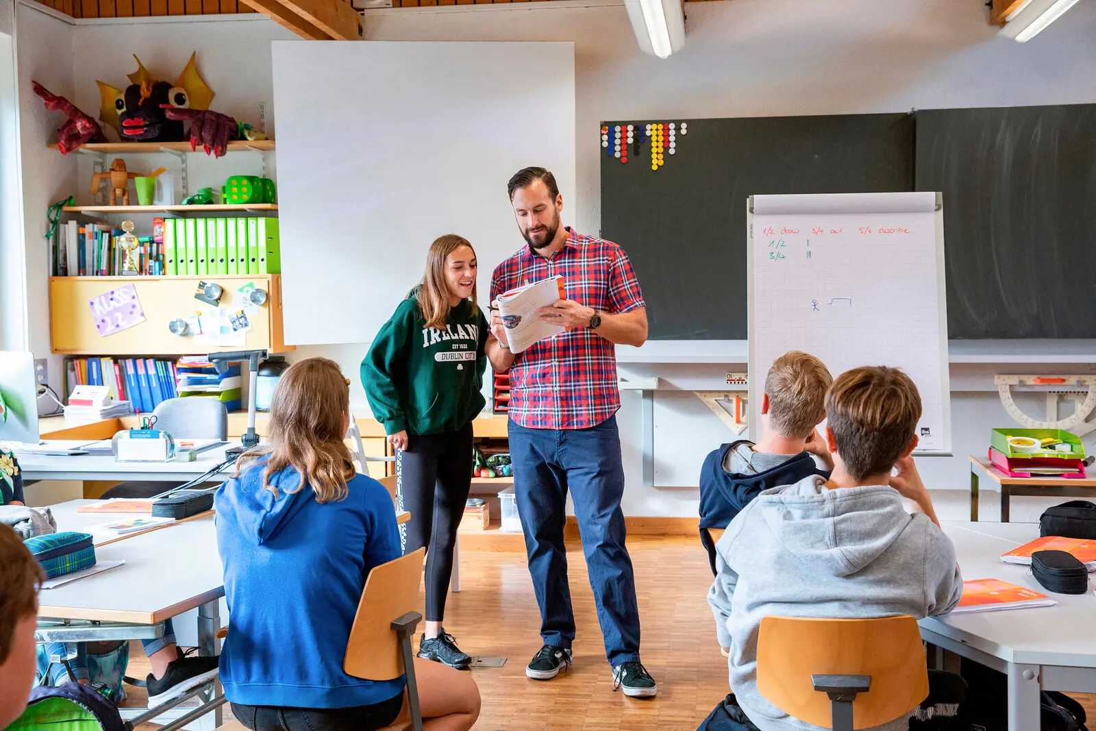 A teacher explains a task to his student in front of the class.