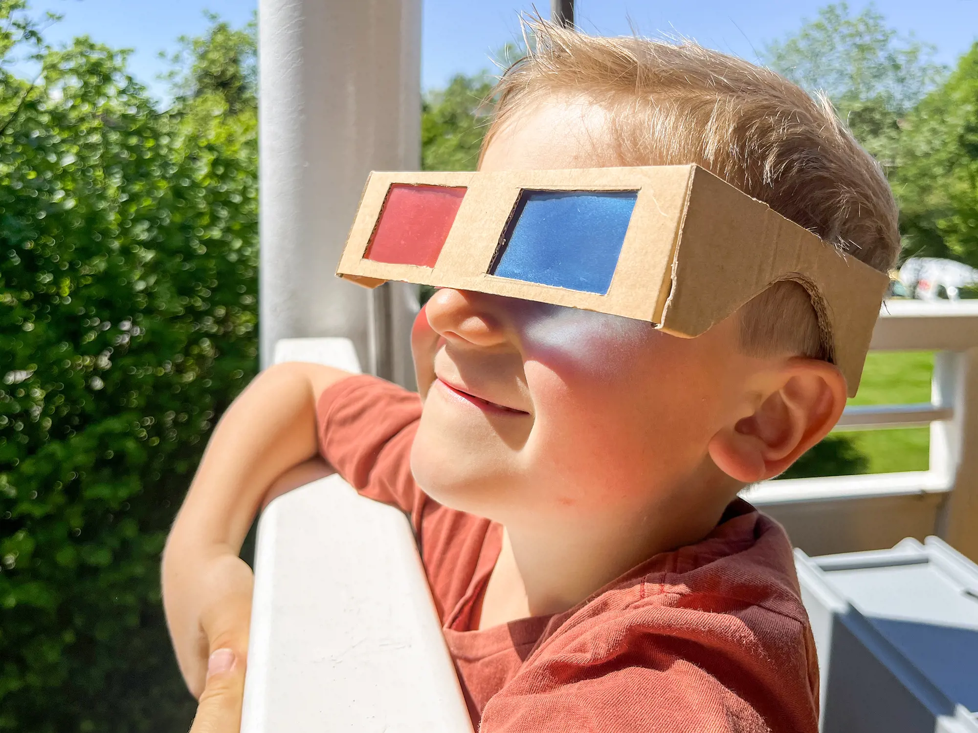 Ein Junge steht am Geländer einer Veranda trägt eine 3D-Brille.