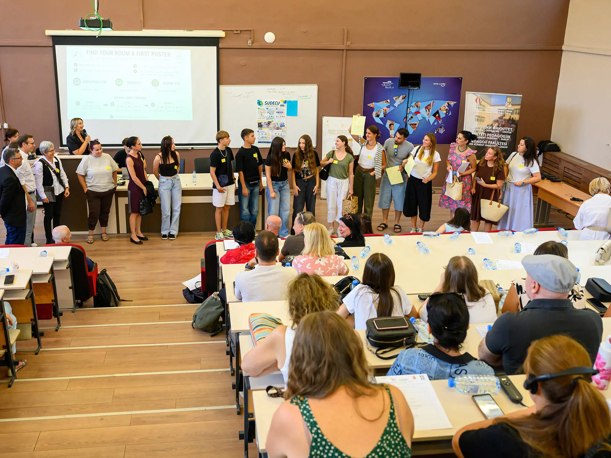 Lokale Freiwillige präsentieren an der SUDECU-Abschlusskonferenz in einem Hörsaal die Ergebnisse ihrer Projekte vor einem Publikum.