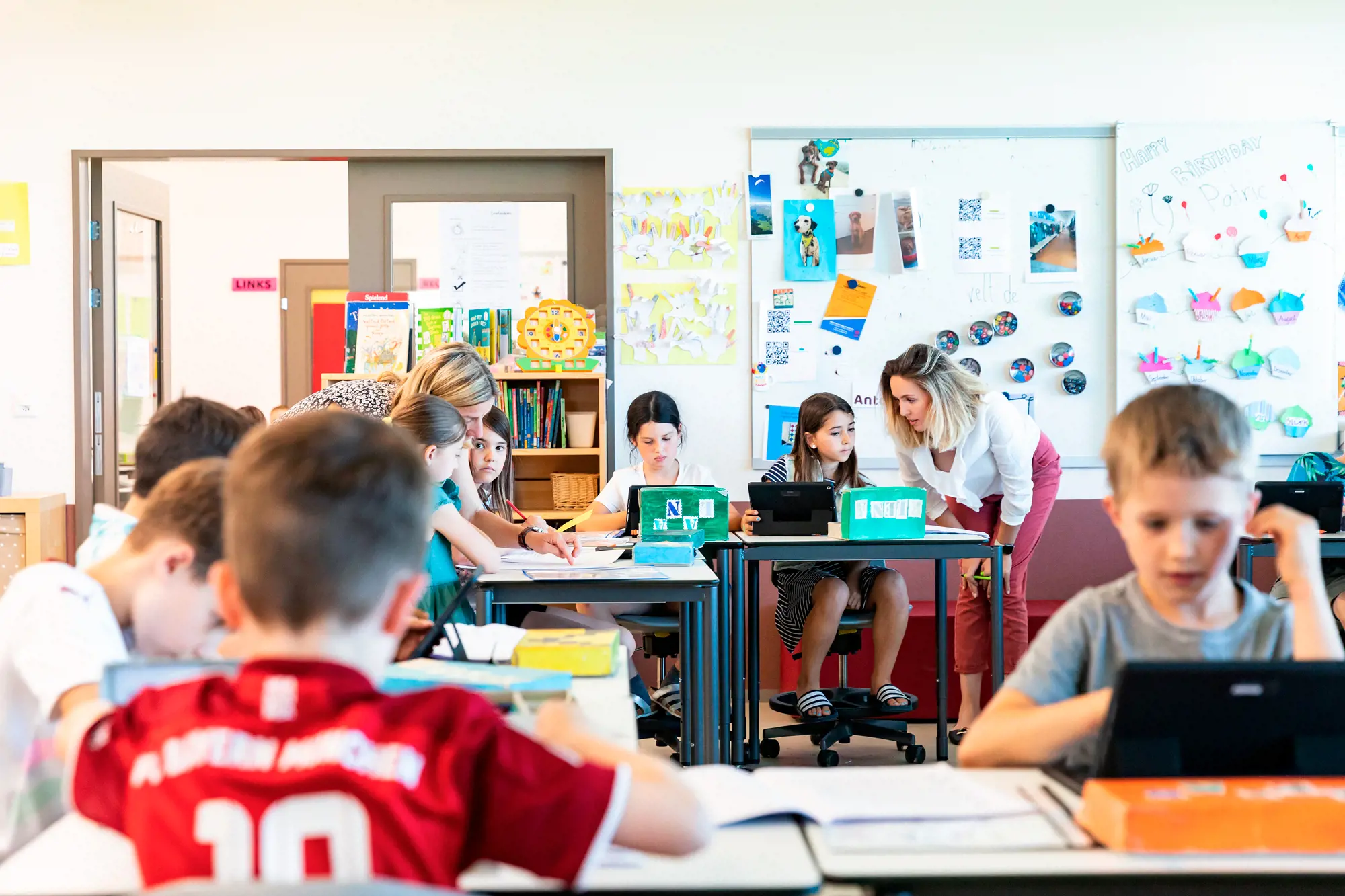 Zwei Lehrerinnen unterstützen Schüler:innen während des Unterrichts.